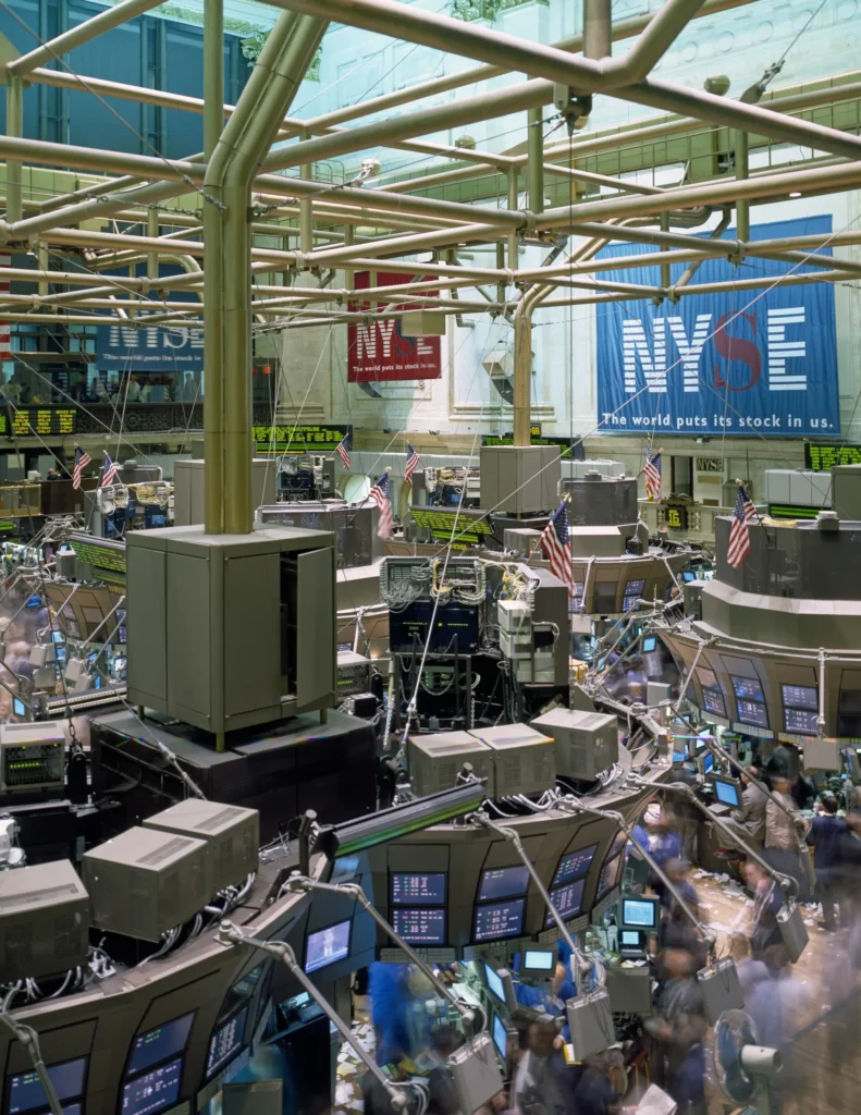 What Ordinary Investors Should Watch in the AI Bubble Debate Traders and financial data screens in a busy stock market setting